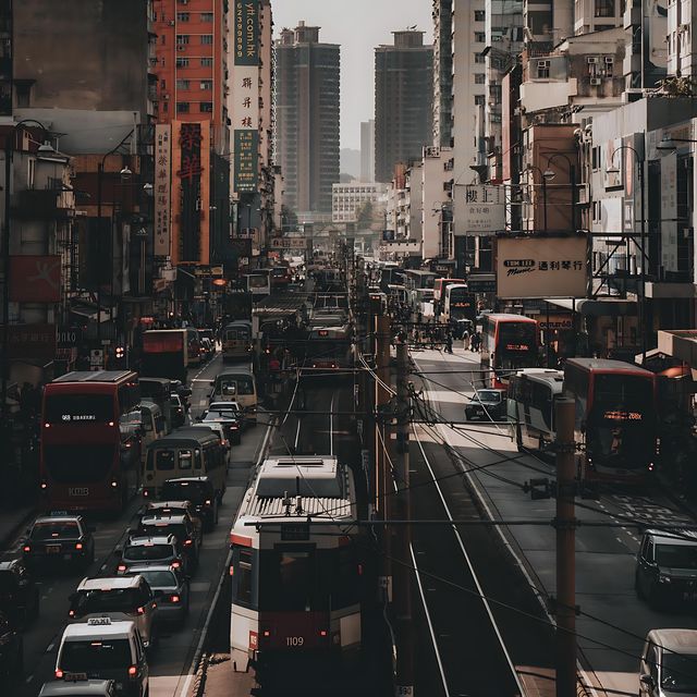 A Hong Kong tram and dense traffic moving through a canyon of buildings in warm late-afternoon light.