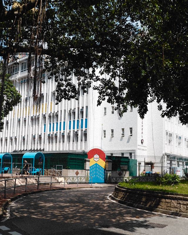 A white building with a painted rainbow arch in a quiet Hong Kong courtyard.