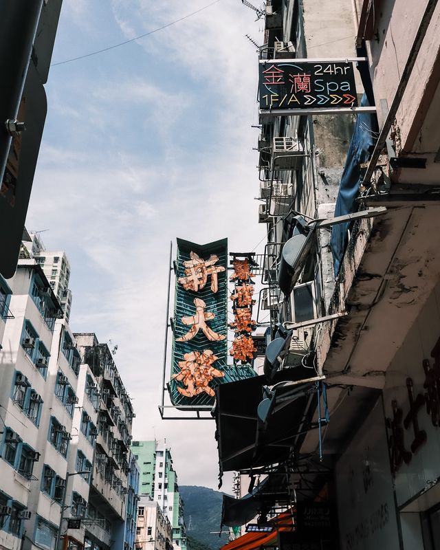 Layered shop signs and old buildings seen from a low angle in Hong Kong.