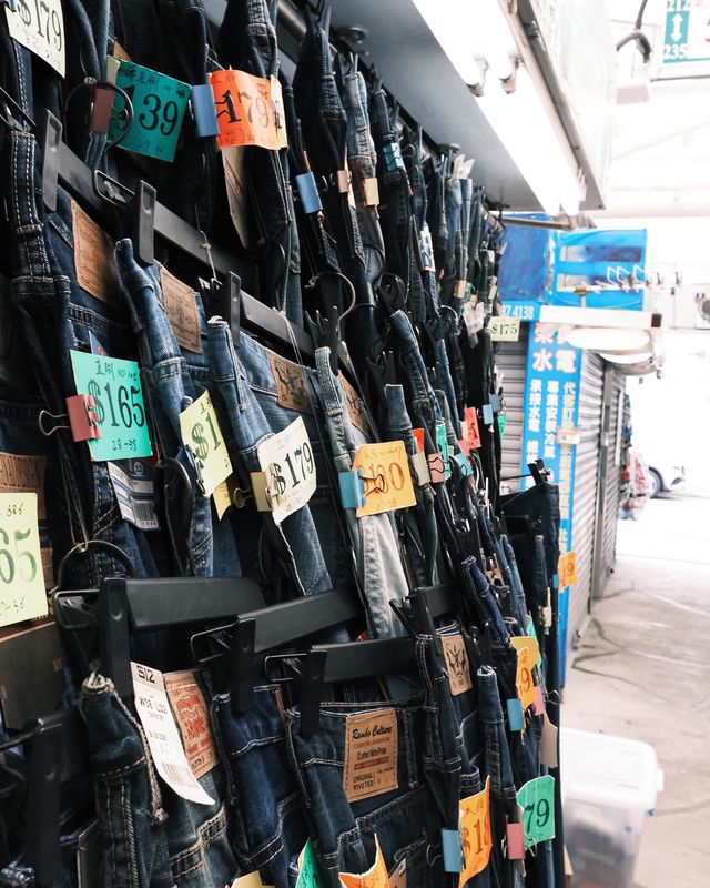 Dozens of bags and garments hanging in dense layers at a market stall.
