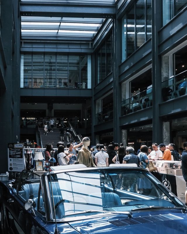 A blue car surrounded by visitors at a Hong Kong indoor car meet.