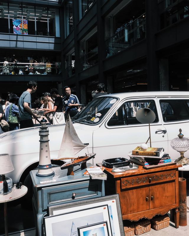 A market stall crowded with vintage cameras, wooden boxes, and small antiques.