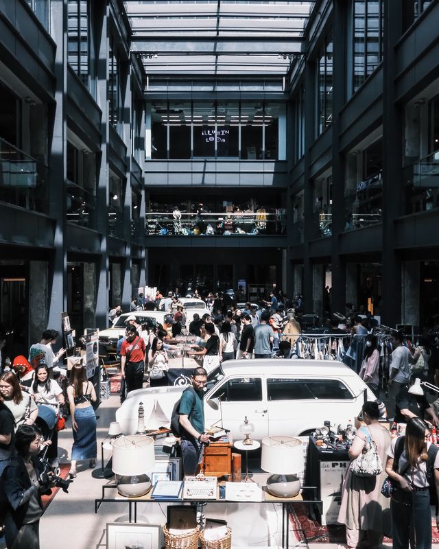 A crowd gathered around white cars in a covered courtyard, seen from above.