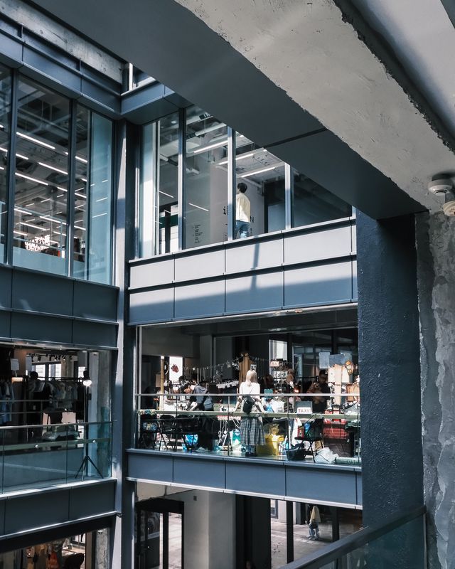 An industrial courtyard with glass roofs and people moving between levels.