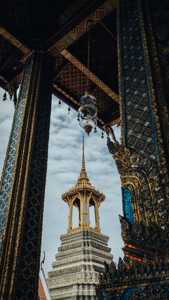 A temple spire seen through an ornate dark frame, with gold details catching the light.