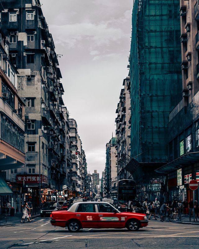 A red car parked on a Taipei street at dusk.