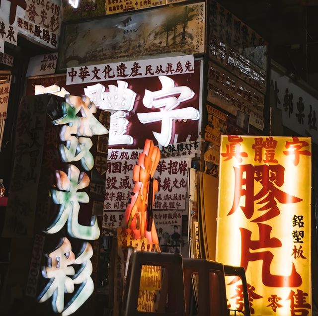 Neon signs and a lit shop entrance after dark in Hong Kong.