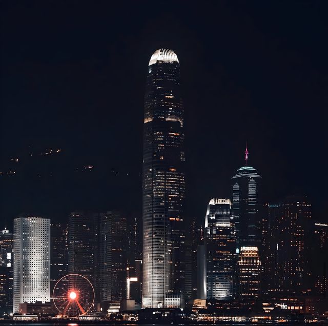 The Hong Kong skyline at night, its lights reflected in the harbour.