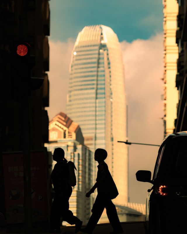 A silhouetted Hong Kong building against a warm dusk sky.