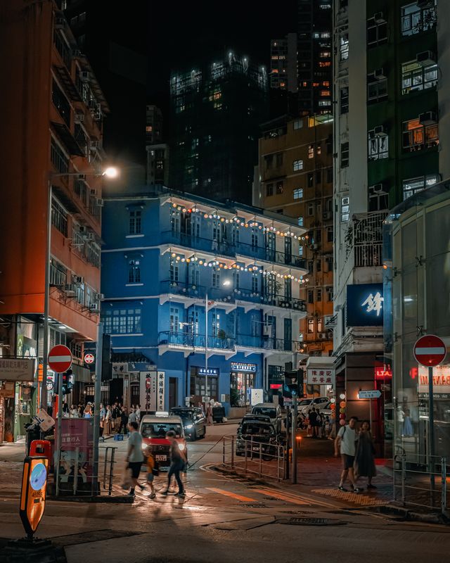 A blue corner building lit at night on a Hong Kong street.