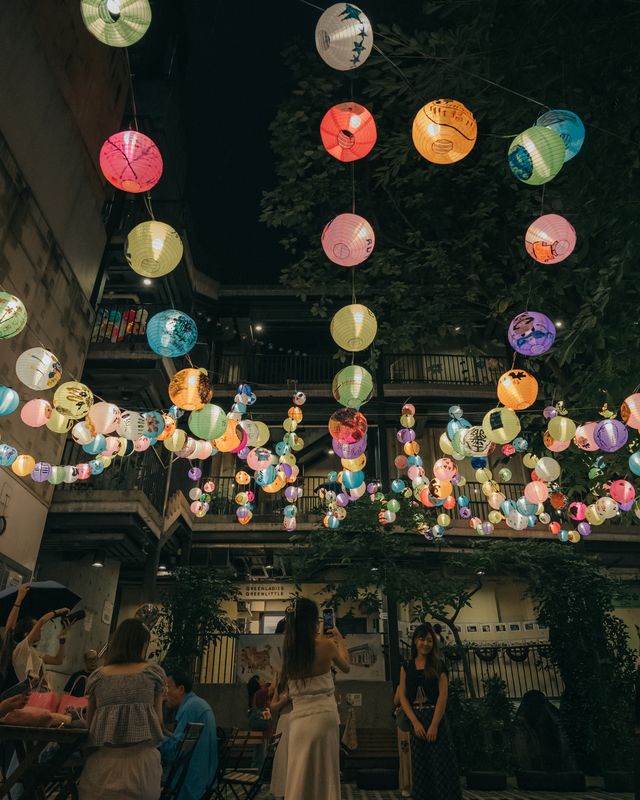 Pink and yellow lanterns hanging above a festival crowd.