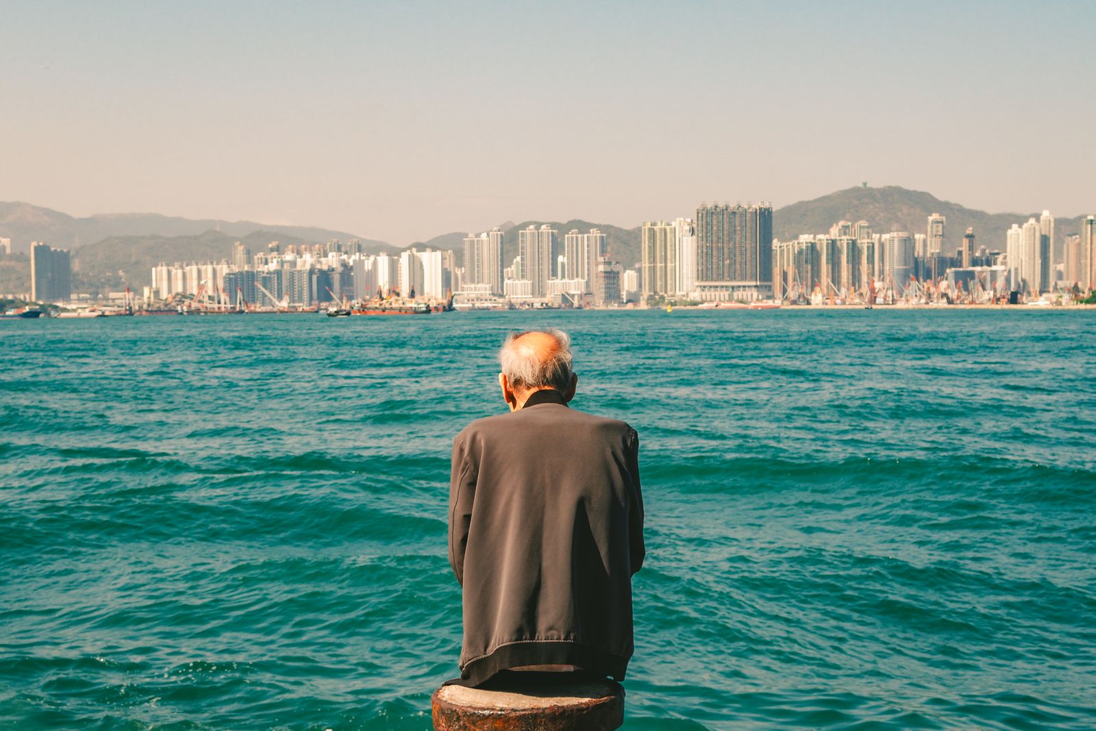 A person standing at the edge of the sea, looking out.