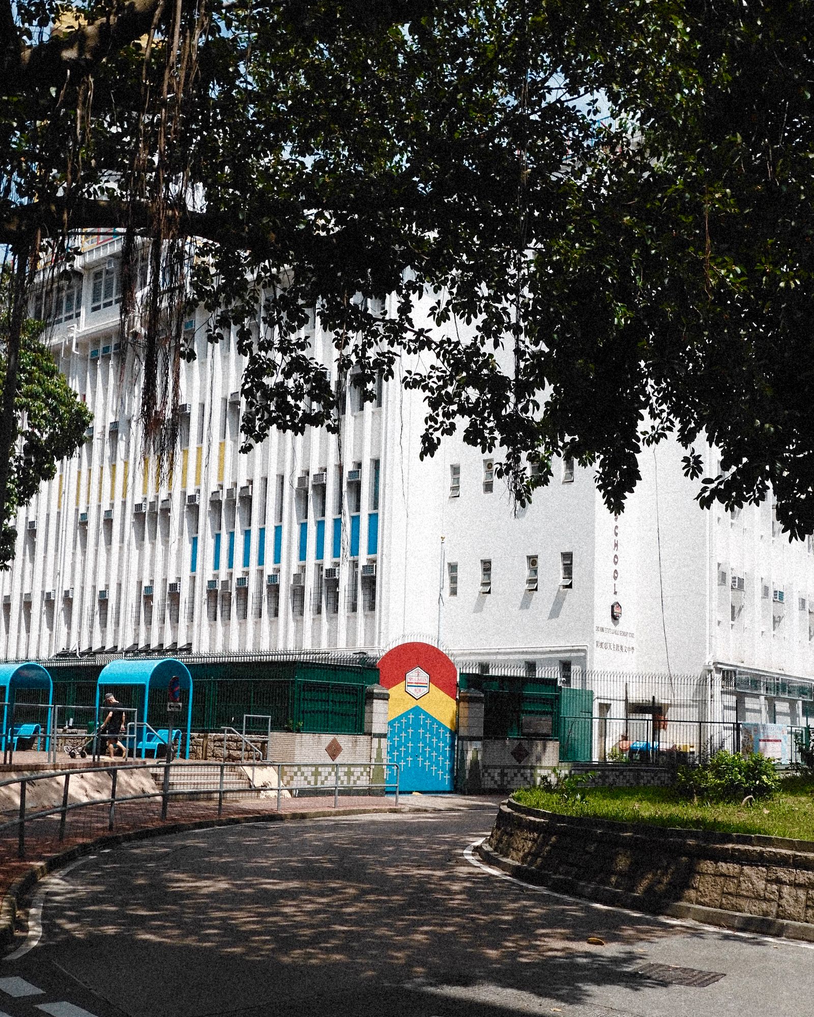 A white building with a painted rainbow arch in a quiet Hong Kong courtyard.
