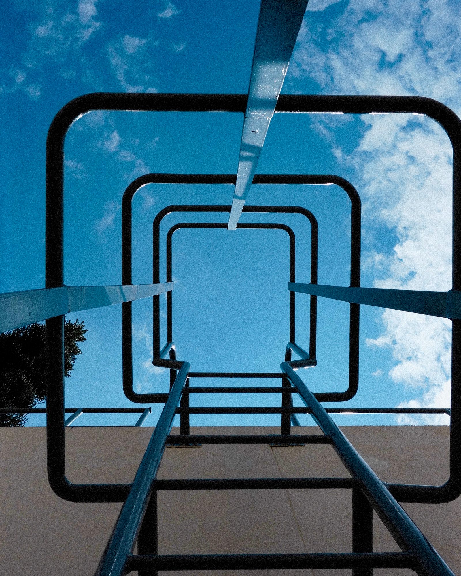 Looking up through a basketball hoop frame at a blue sky and a tall housing block.