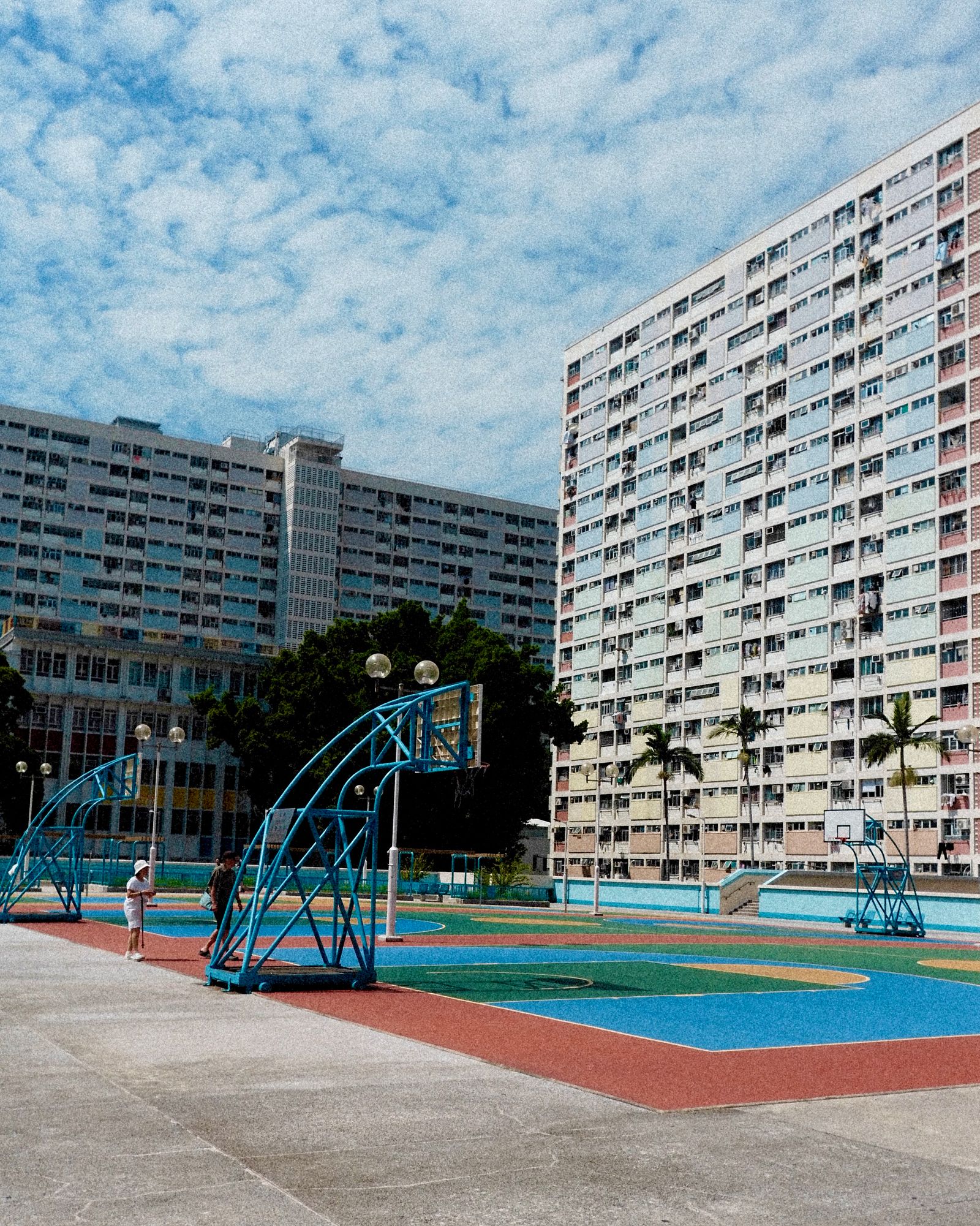 A colourful estate courtyard with a basketball court and repeating residential blocks.