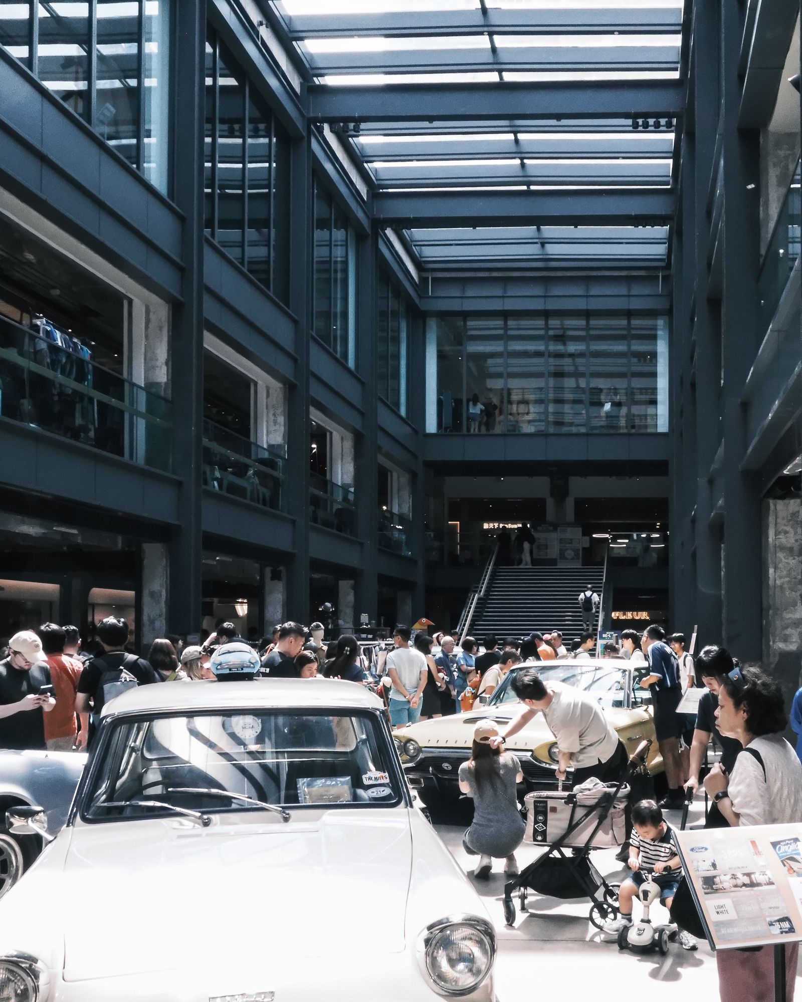 White cars parked inside an industrial building with people gathered around them.