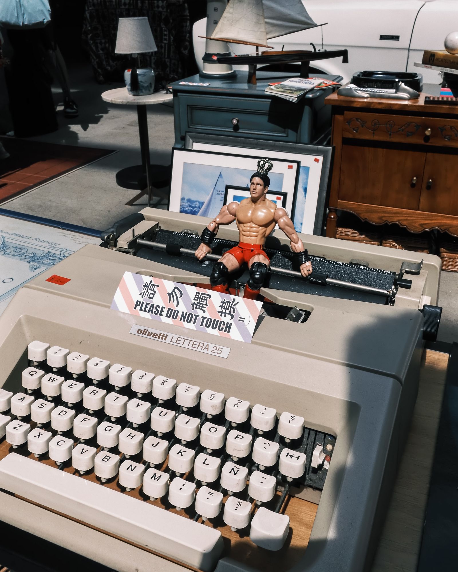 A vintage typewriter on a table with a small toy figure and a name card.