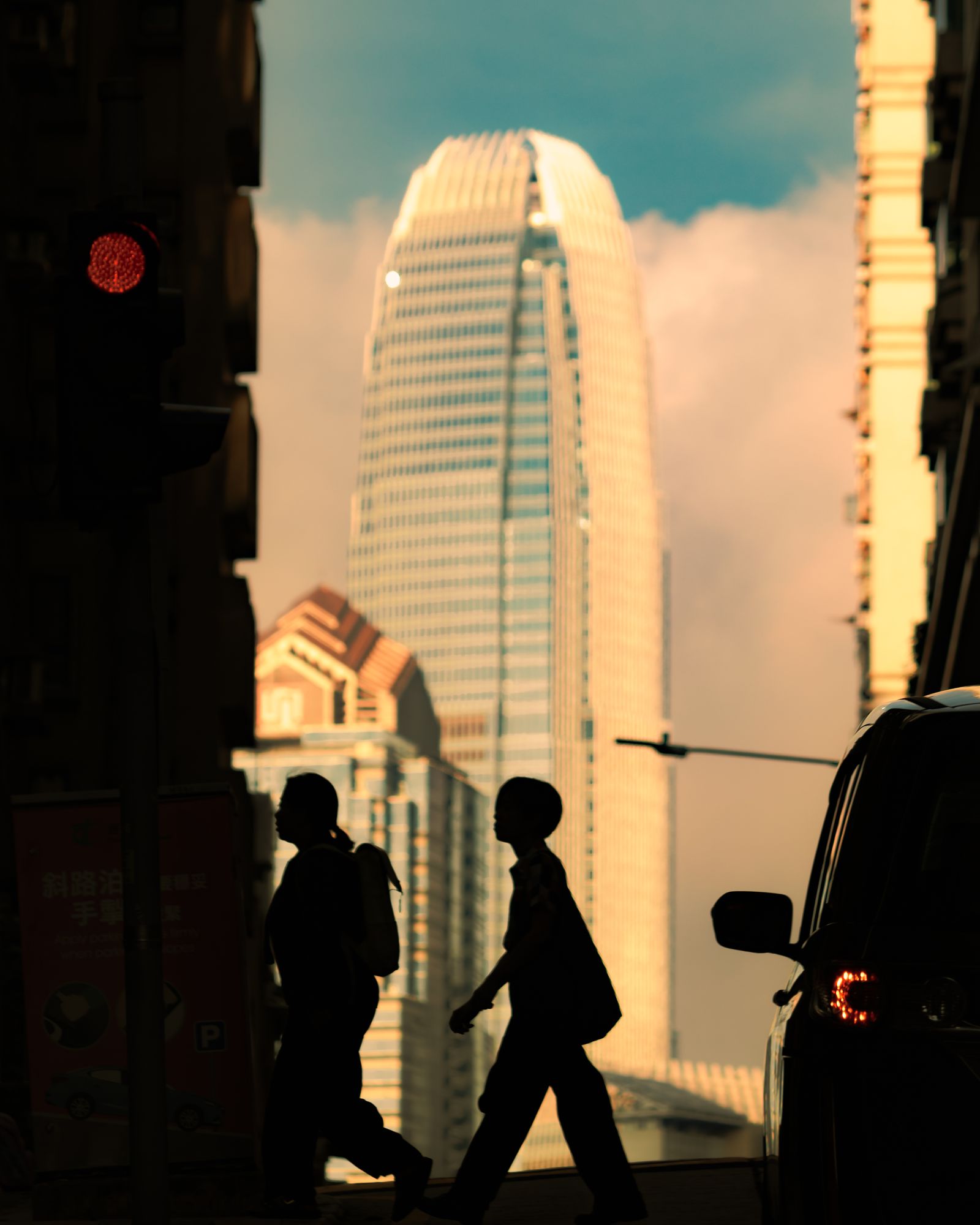 A silhouetted Hong Kong building against a warm dusk sky.