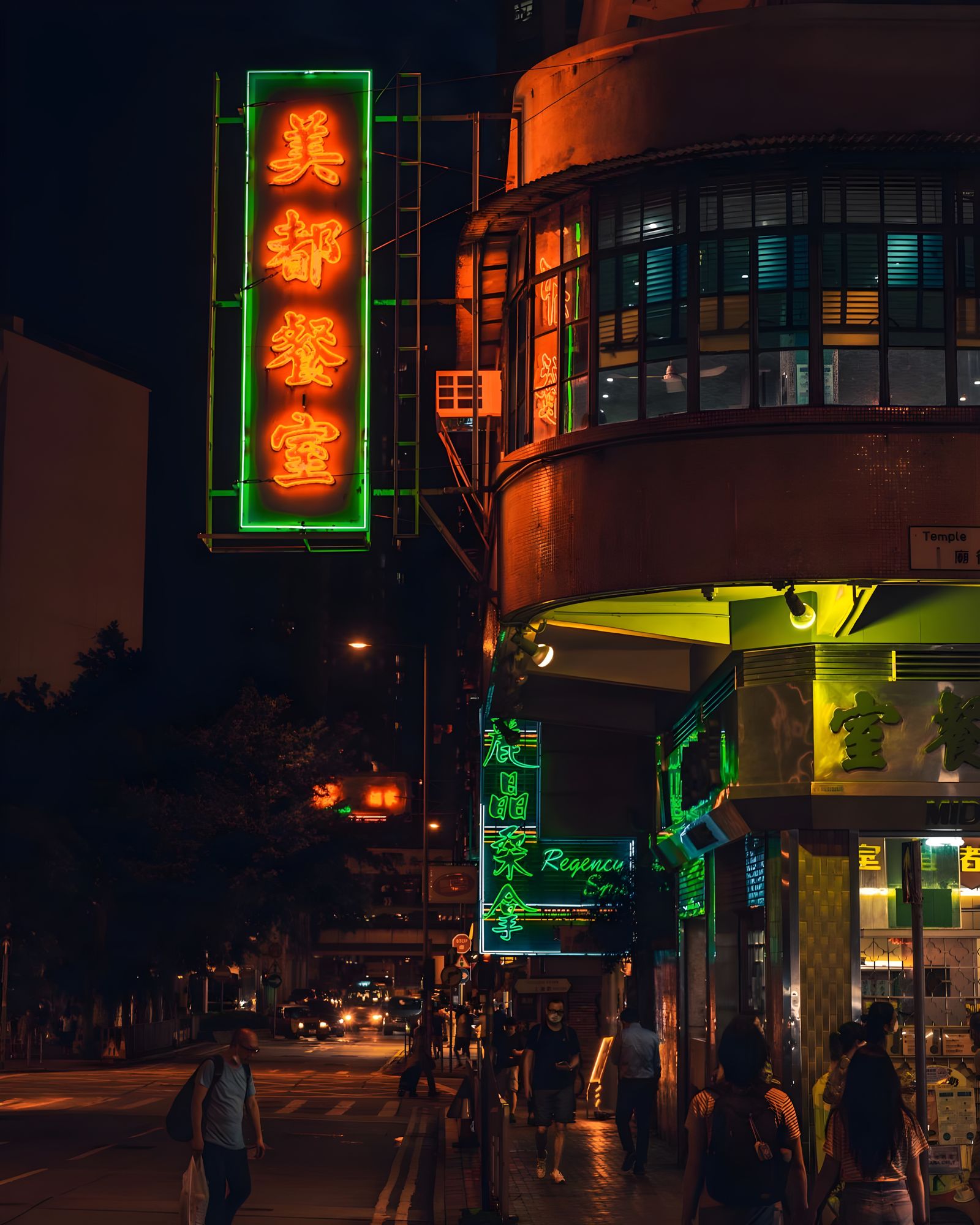 A Hong Kong street corner at night, with green and orange neon signs.