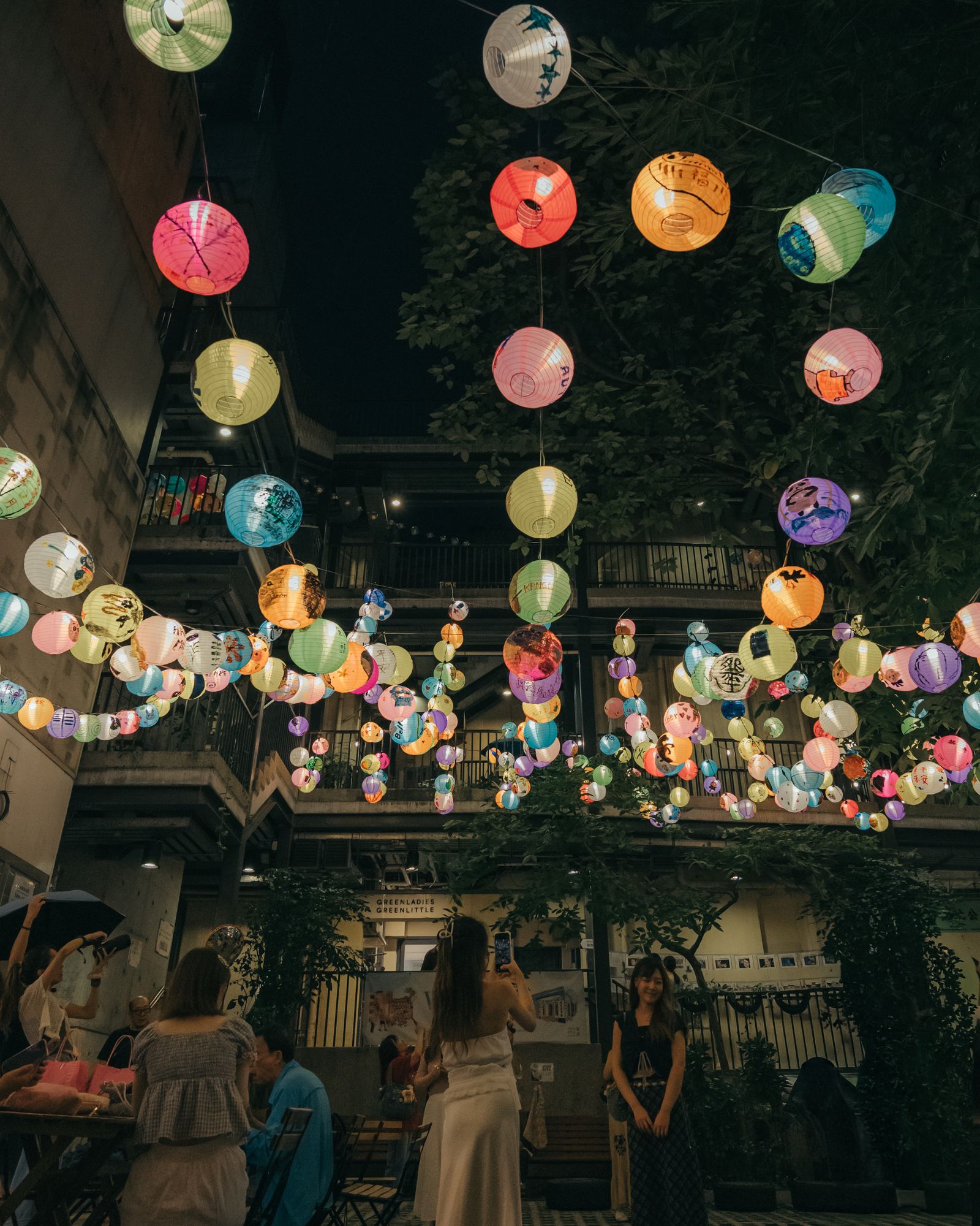 Pink and yellow lanterns hanging above a festival crowd.