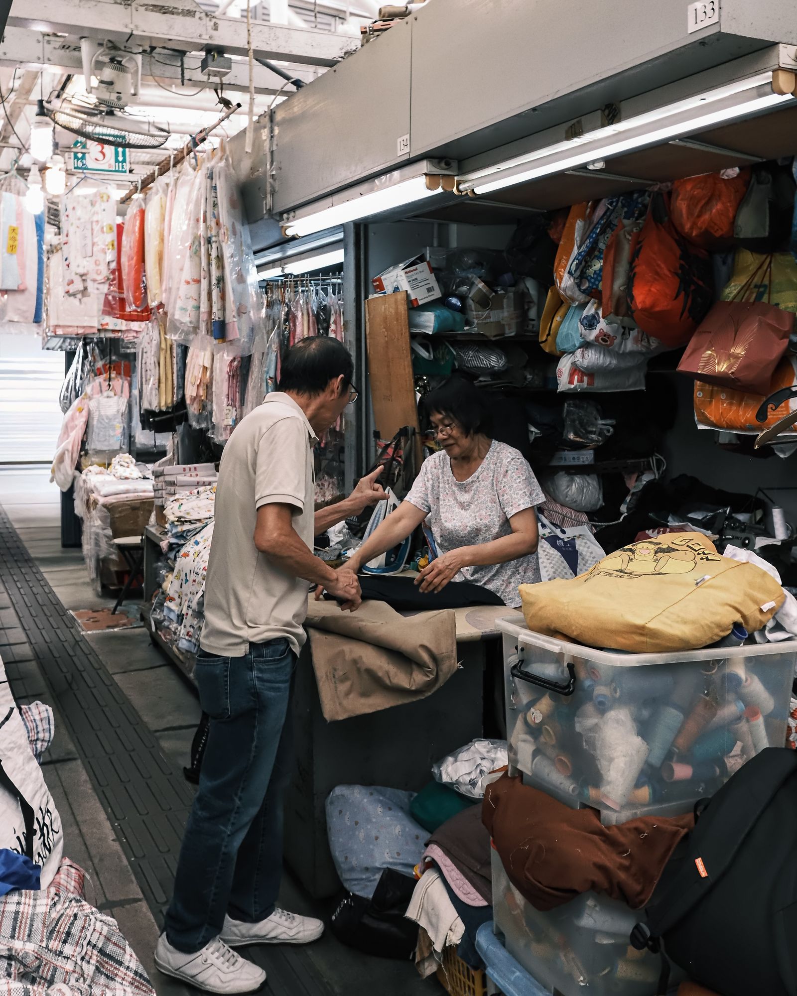 A busy market stall with people browsing under warm artificial light.