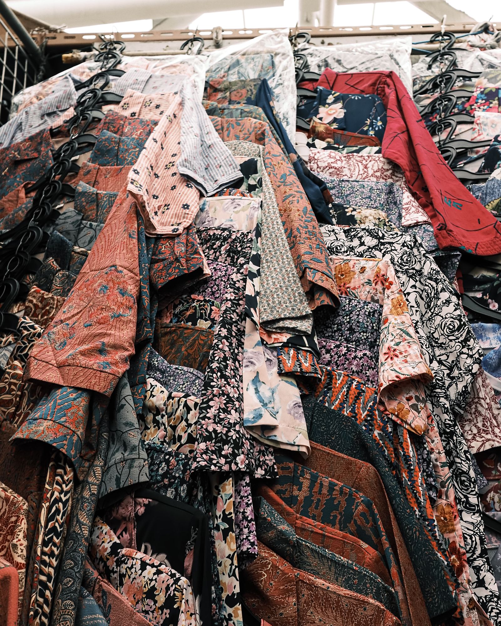 Closely packed patterned garments hanging in a market stall.
