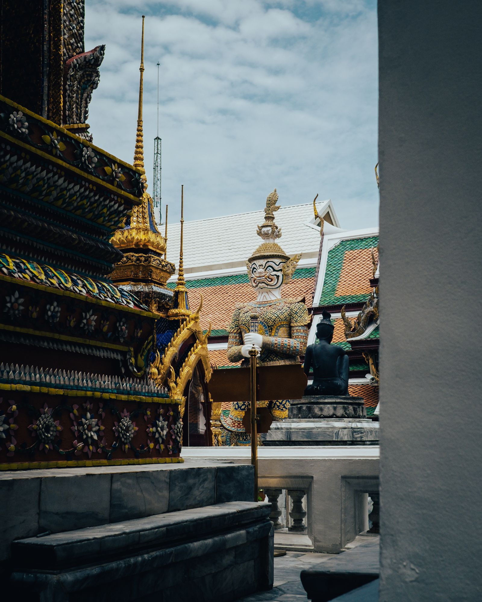 A golden stupa seen past a dark temple pillar and ornate roof details.